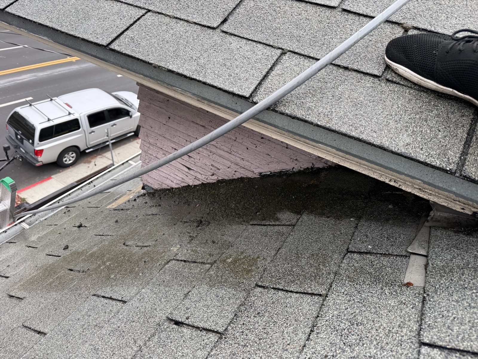Before — wet grime and debris at a Berkeley roof eave beside a painted brick chimney