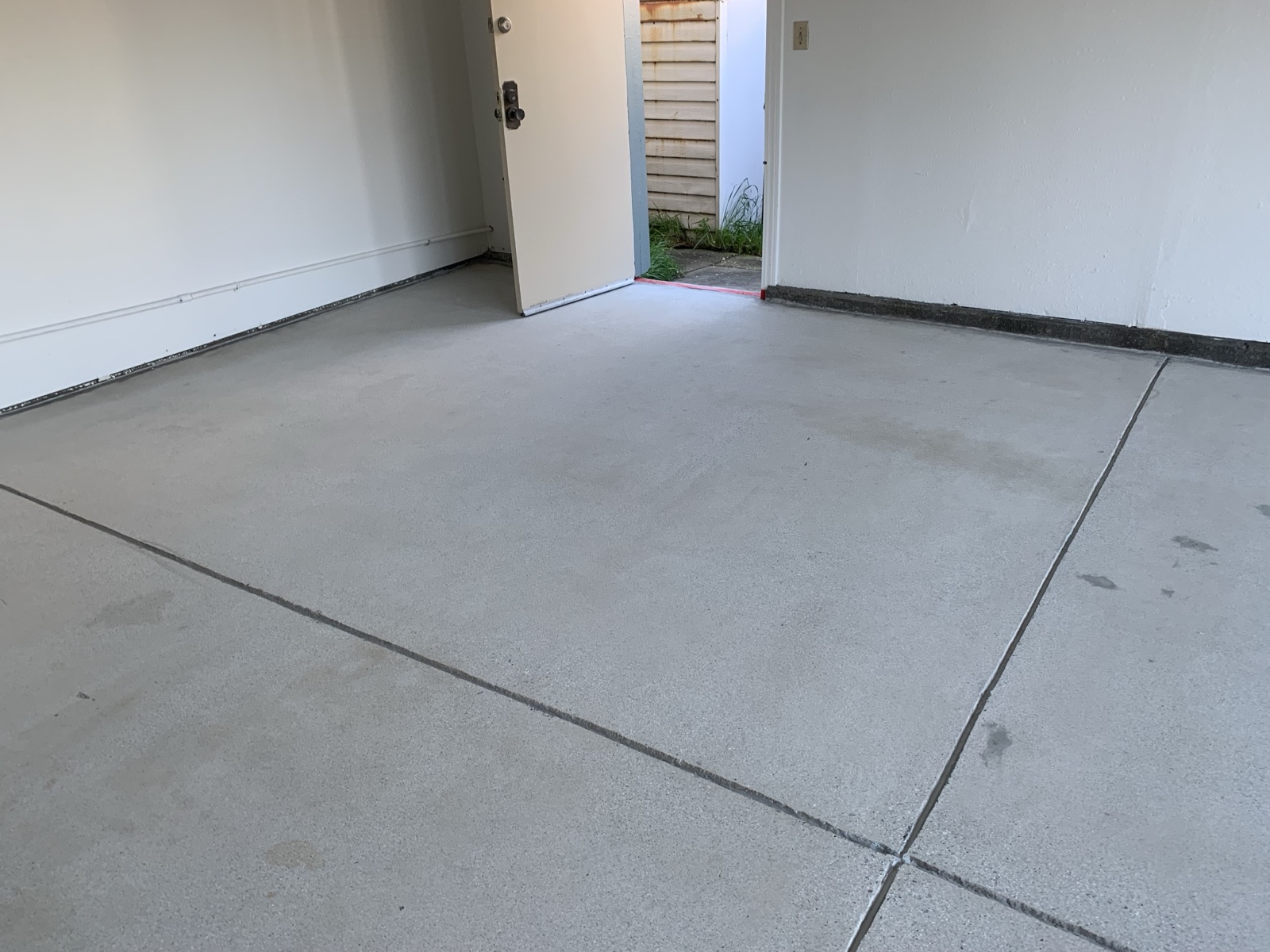 Before — bare concrete garage floor at the side door in Fremont before solid color epoxy
