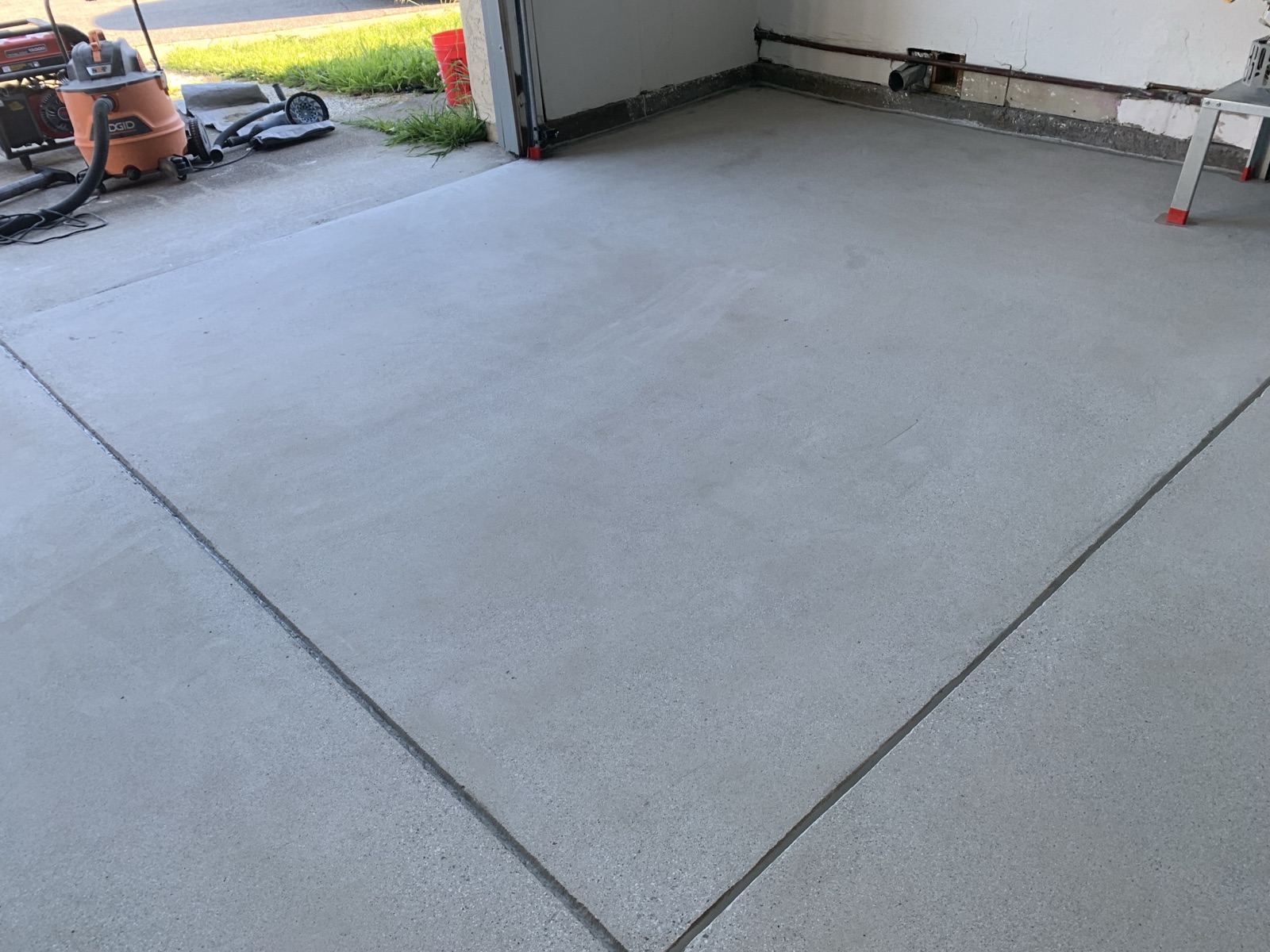 Before — bare Fremont garage floor with grinder and vacuum staged before epoxy prep