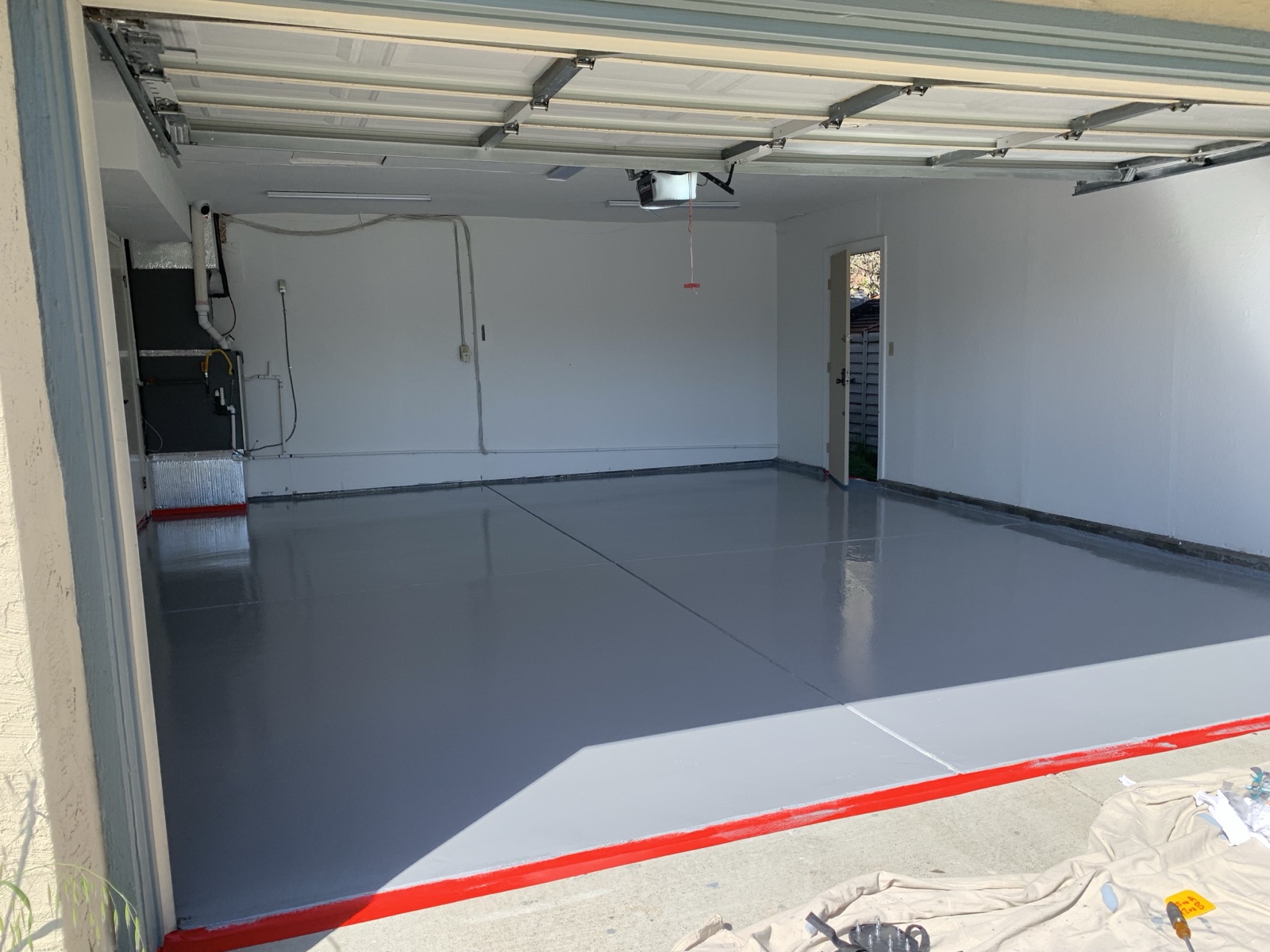 After — glossy grey epoxy garage floor with red trim in Fremont after coating