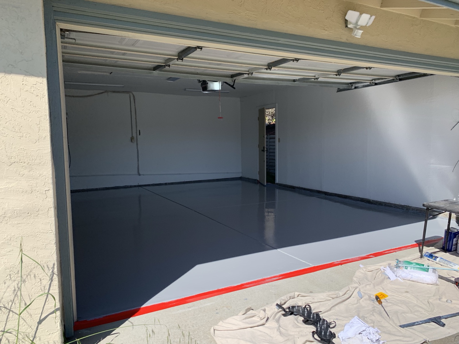 After — completed Fremont garage epoxy floor viewed from the driveway with a red border line