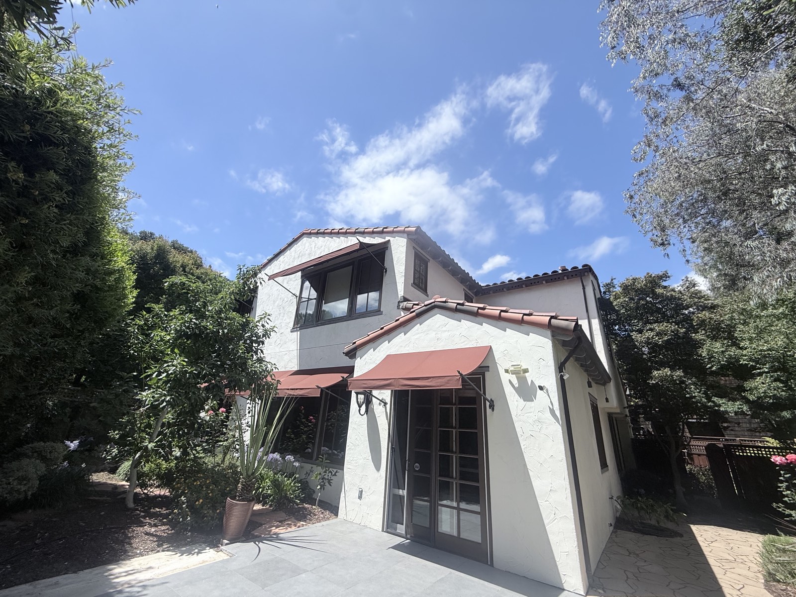 After — rear of the Los Gatos home with clean stucco, terracotta awnings, and French doors over the patio