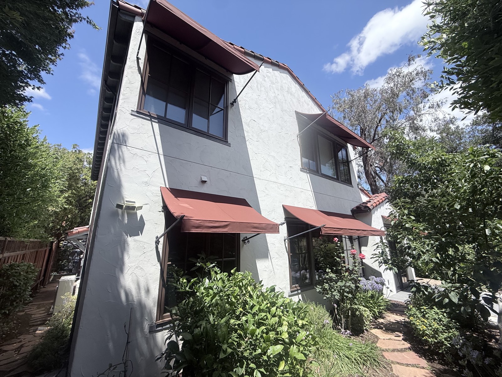 After — two-story side elevation of the Los Gatos home clean, awnings and garden beds framing the stucco