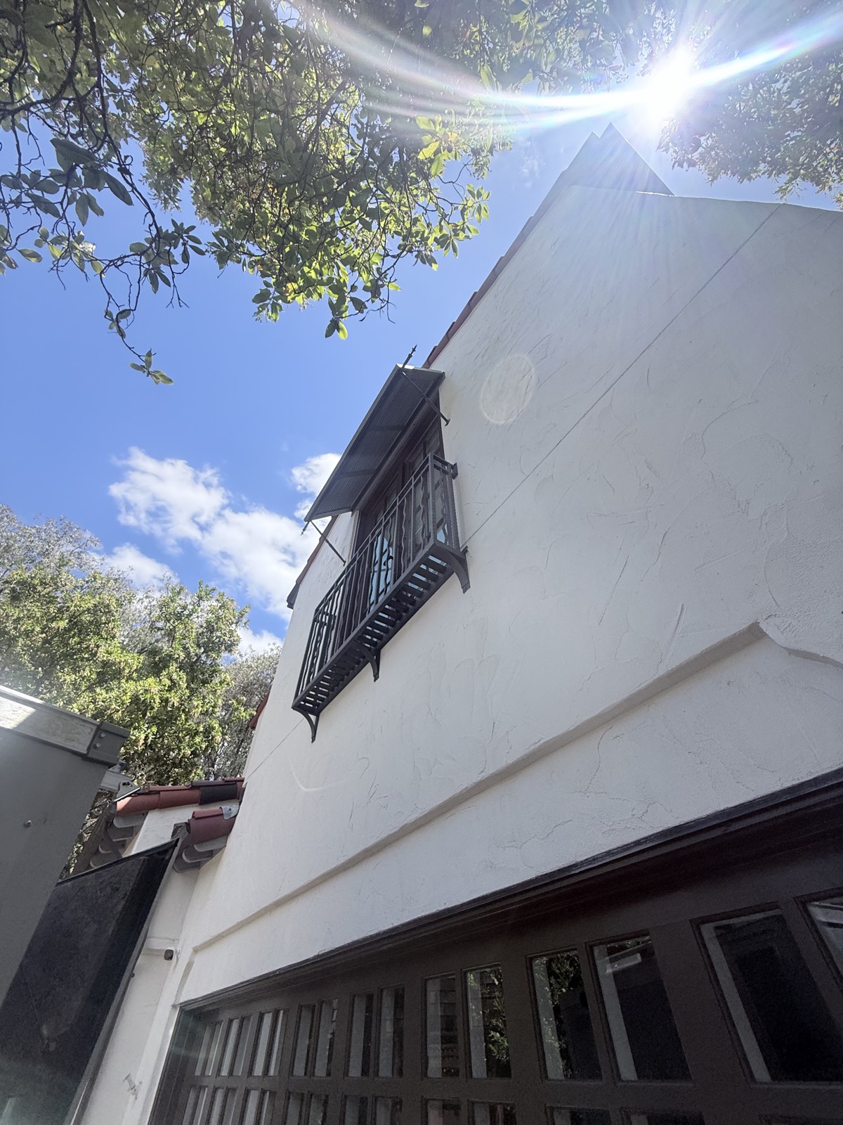 After — gable wall with wrought-iron balcony on the Los Gatos home, stucco washed bright