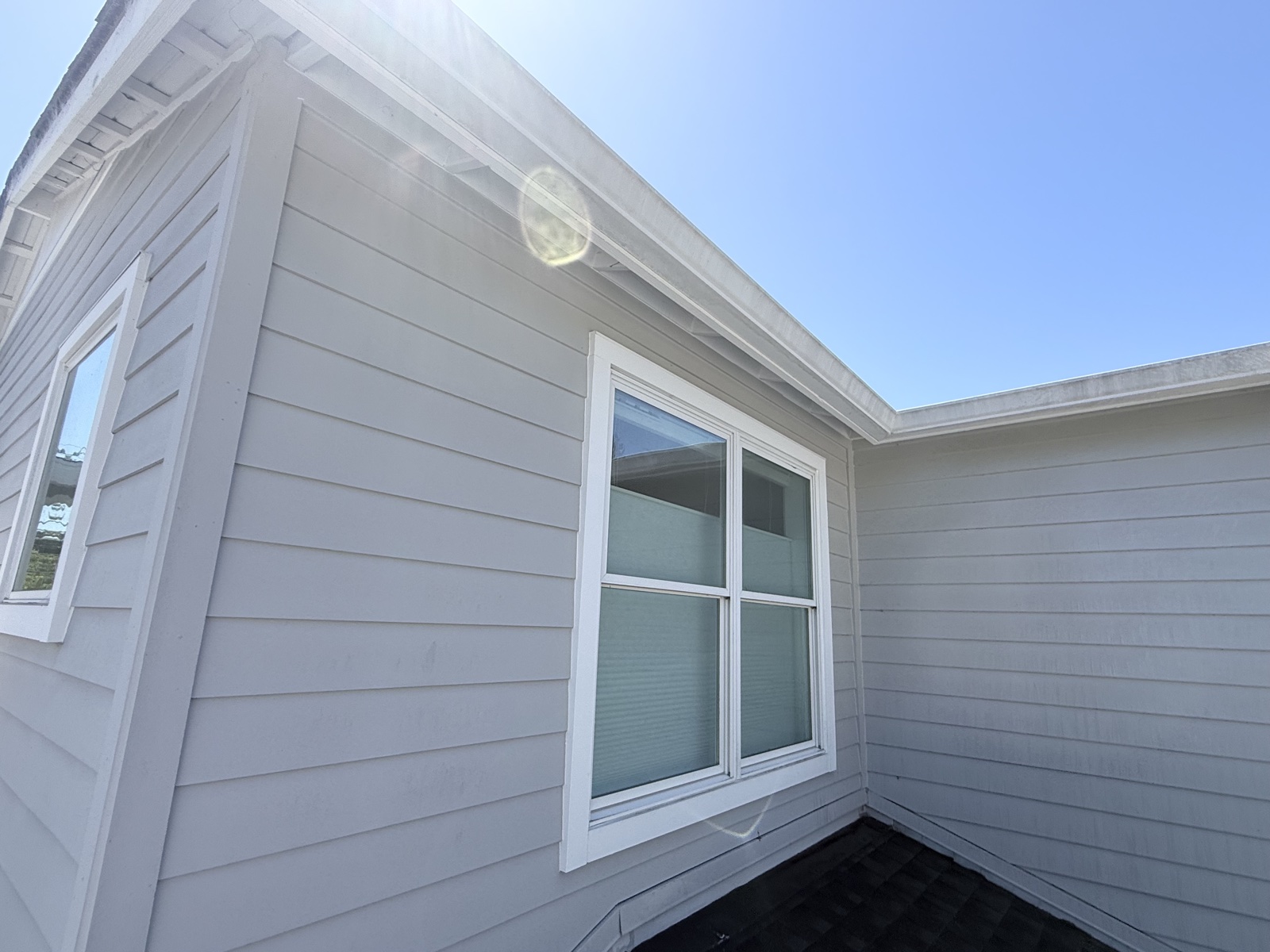 Before — light gray lap siding and white window trim on the upper story of a Menlo Park home with faint dust streaks