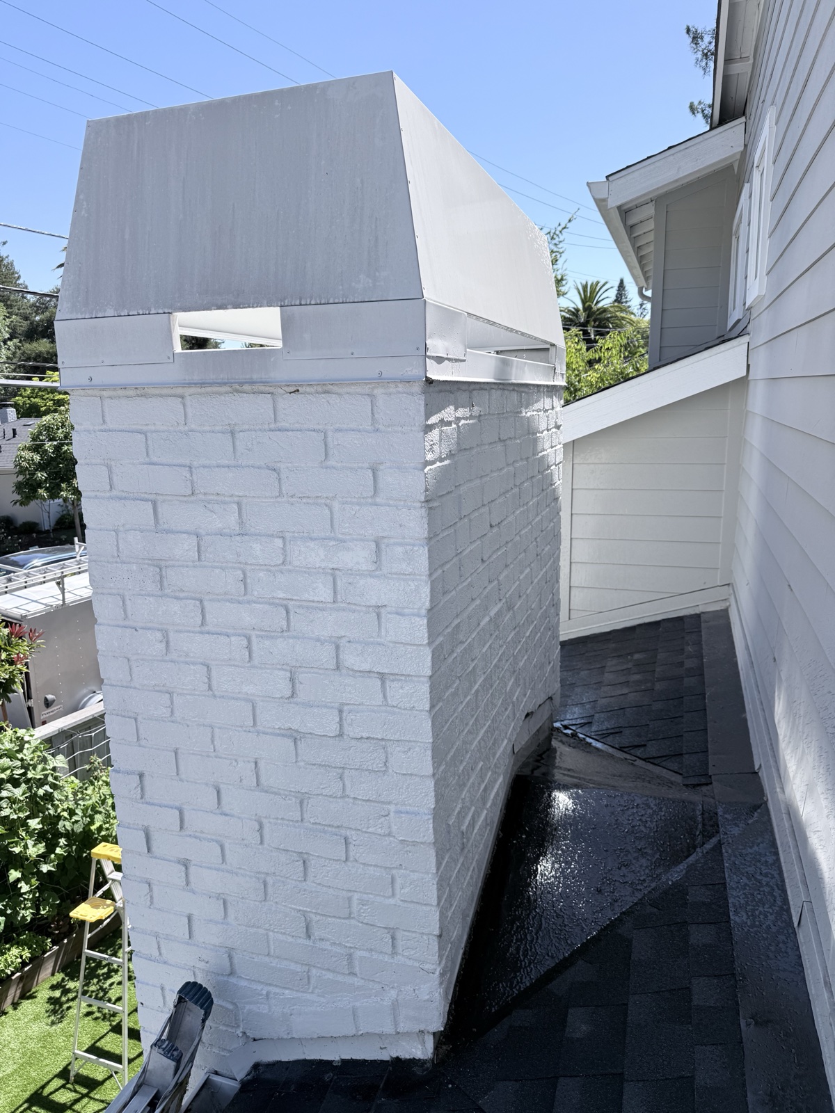 Before — white-painted brick chimney of a Menlo Park home, roof shingles wet with dirty runoff during washing