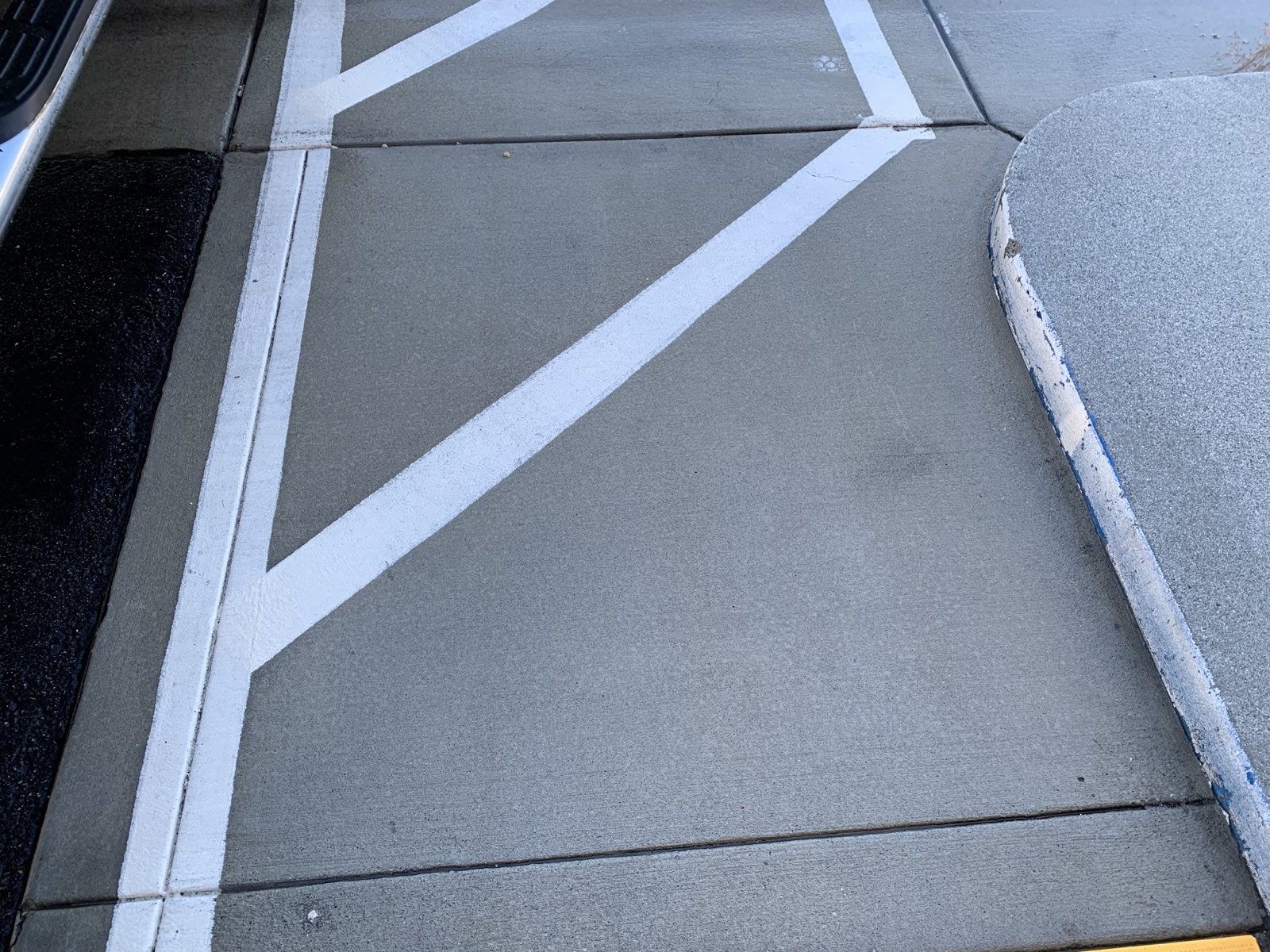 After — walkway concrete uniform again, white parking-lot striping standing out on the cleaned surface