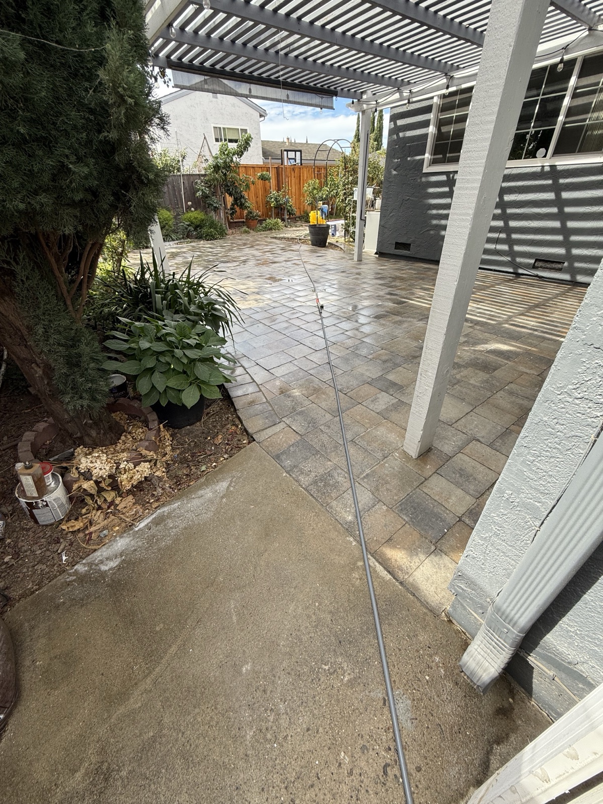 Before — San Jose backyard paver patio dark with grime under the pergola, next to a heavily stained concrete walkway