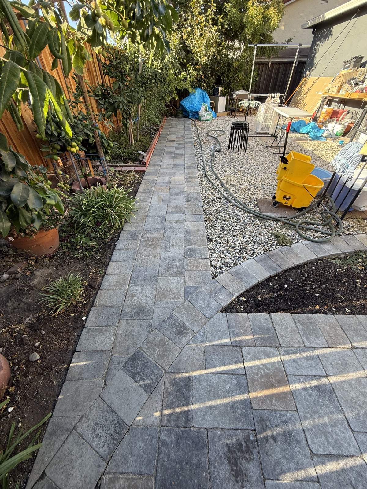 Before — dull, soiled paver walkway running along the side-yard fence and garden beds in San Jose
