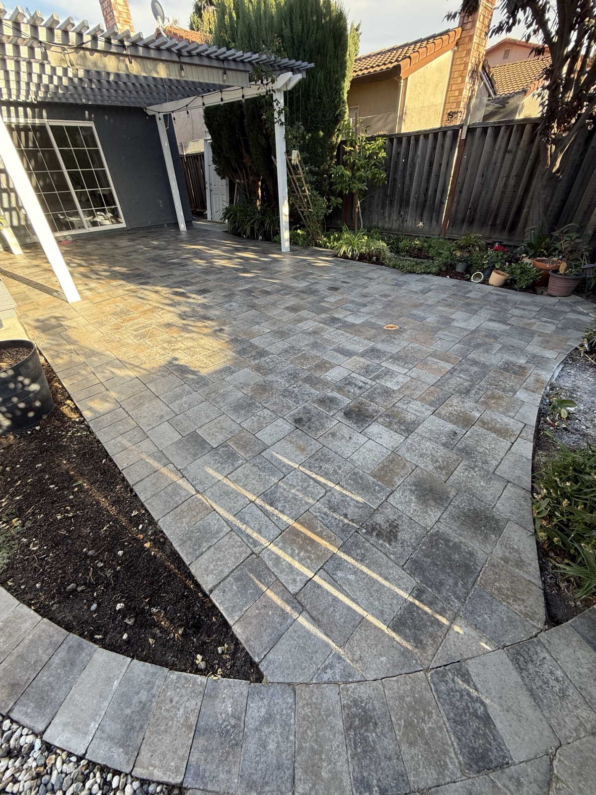 Before — wide view of a San Jose paver patio with blotchy dark staining and faded color before cleaning