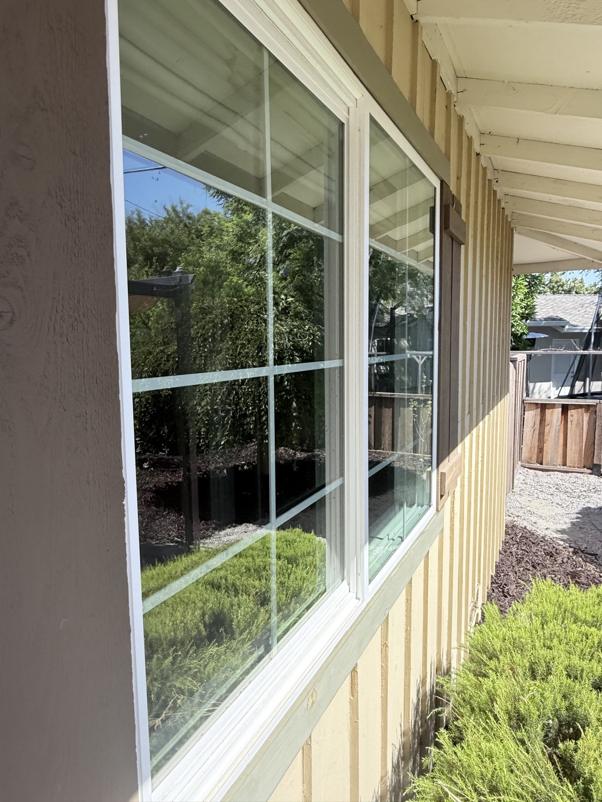 After — clean divided-lite windows on a board-and-batten wall, garden reflected in the glass
